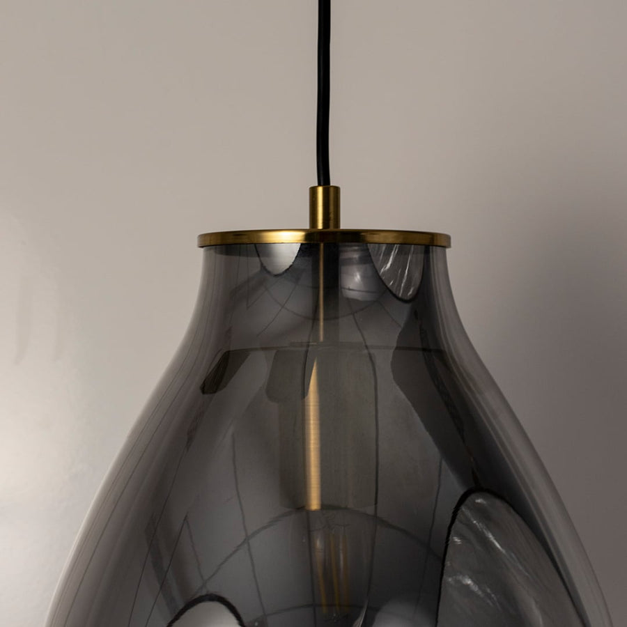 A closeup view of the smoked grey pendant light showing the curved glass surface and warm glowing filament ideal for modern elegant interiors.