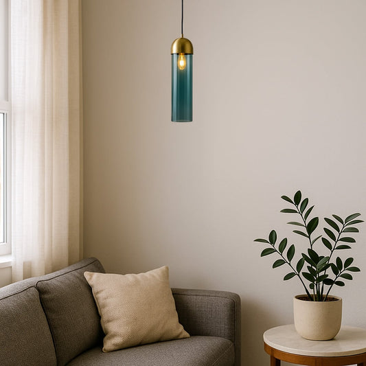 A modern teal glass and gold metal pendant light glowing warmly above a cozy living room corner creating soft ambient lighting for contemporary home decor.
