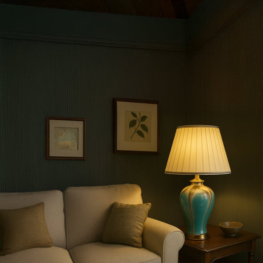Elegant blue ceramic table lamp with white pleated shade styled on a wooden console against paneled wall adding charm to interiors.