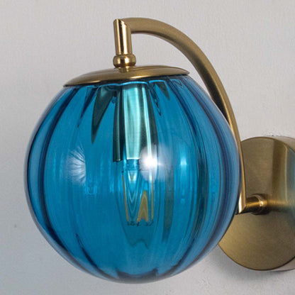 Modern brass wall light with blue ribbed glass globe for luxury contemporary interior styling.