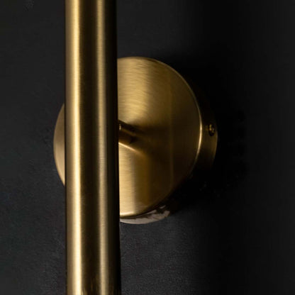 Detailed closeup of gold metal wall light highlighting its slim cylindrical structure and clear bulb form for refined modern decorative lighting.