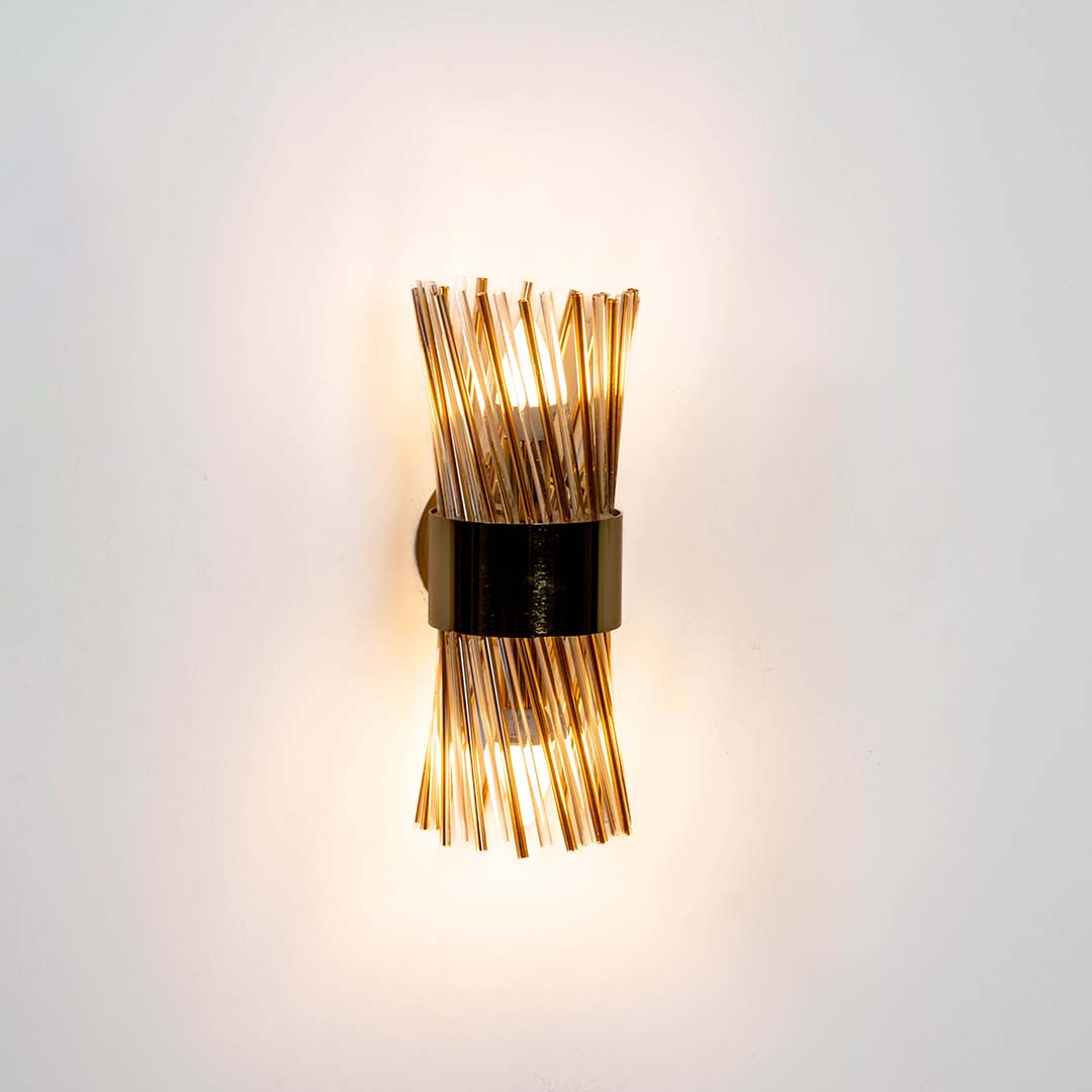 Decorative black and brass wall light with warm glow for stylish modern interior decor.