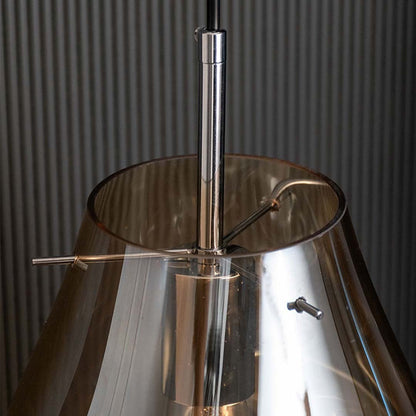 Detailed closeup of amber tinted glass pendant light featuring smooth metallic top and handcrafted glass curves for premium decor.