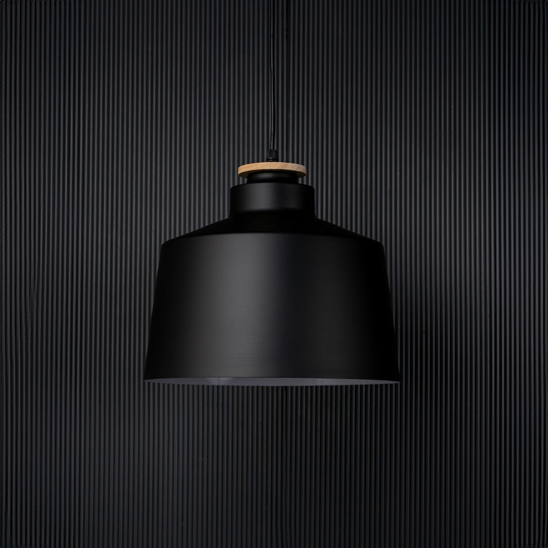 A contemporary black pendant light captured on a black background with the light off emphasising its bold structure and sleek matte finish in a minimalist setting.