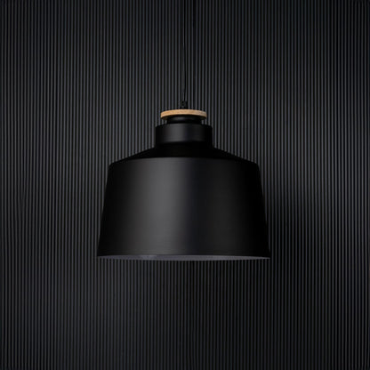 A contemporary black pendant light captured on a black background with the light off emphasising its bold structure and sleek matte finish in a minimalist setting.