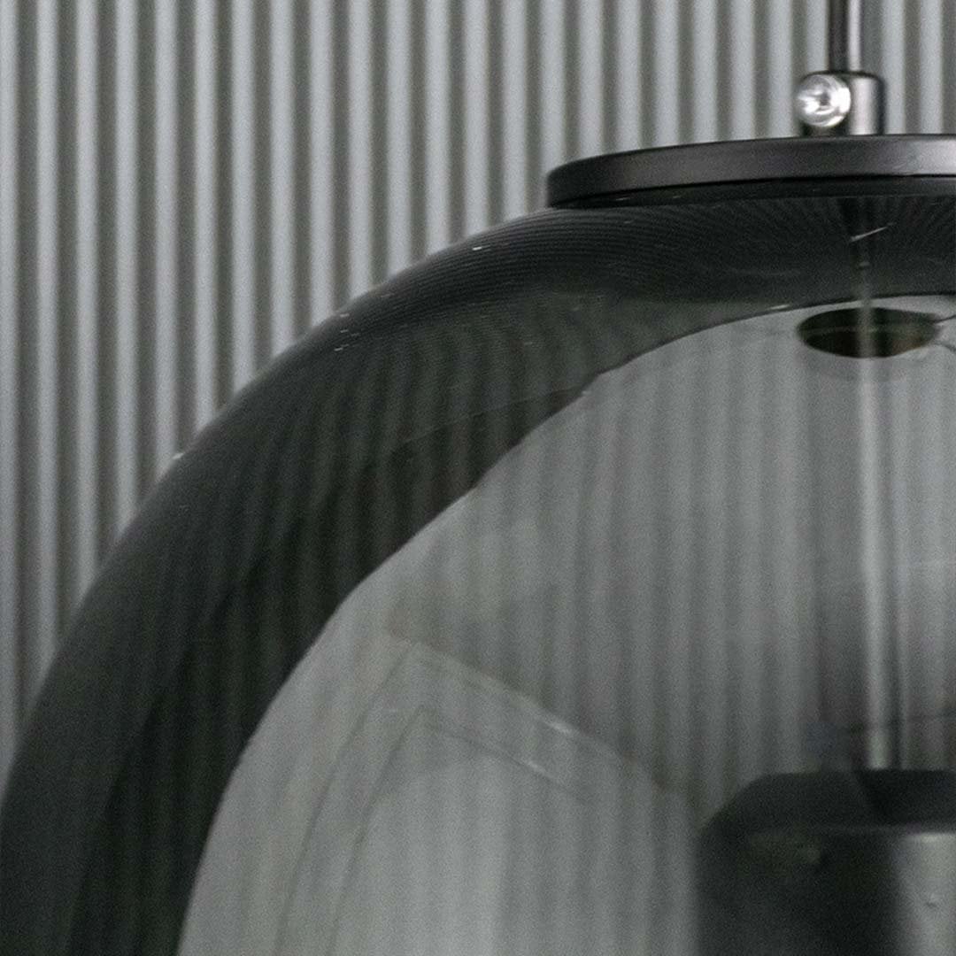 Detailed closeup of the smoked glass pendant light showing the glowing bulb and reflective curved dome surface.