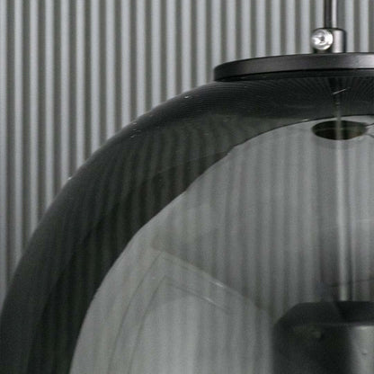 Detailed closeup of the smoked glass pendant light showing the glowing bulb and reflective curved dome surface.