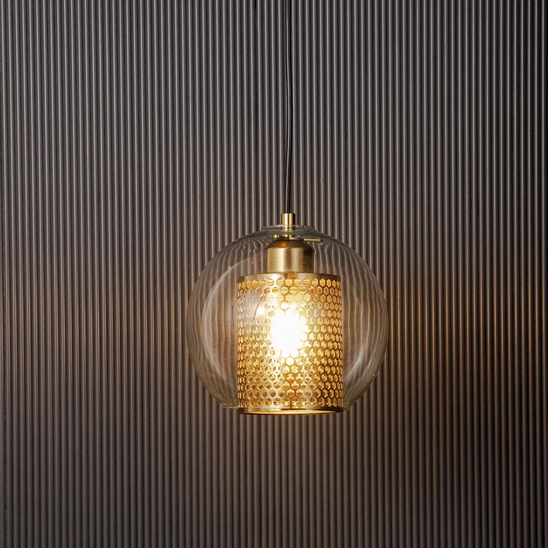 Golden glass pendant ceiling lamp glowing warmly against dark background modern interior lighting.
