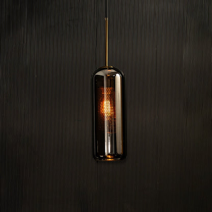 Tall smoked grey glass pendant with gold fitting and warm glowing diffuser highlighted on a dark background creating a dramatic stylish lighting accent.