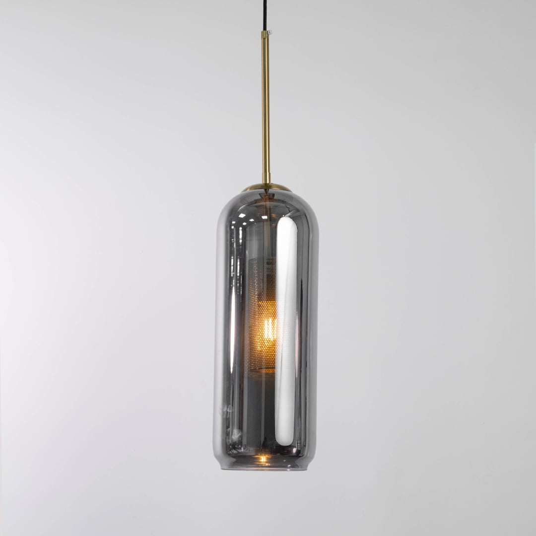 Smoked grey glass cylindrical pendant with warm glowing inner diffuser and gold fitting shown on a white background for modern decor styling.