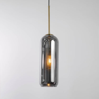 Smoked grey glass cylindrical pendant with warm glowing inner diffuser and gold fitting shown on a white background for modern decor styling.