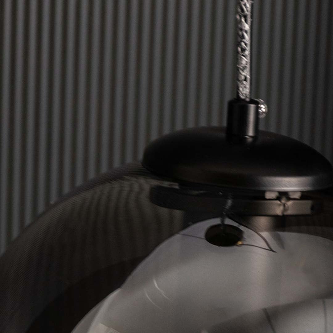 Closeup off Smoked black glass pendant light displayed unlit on a black background showcasing its sleek round form and modern decorative style.