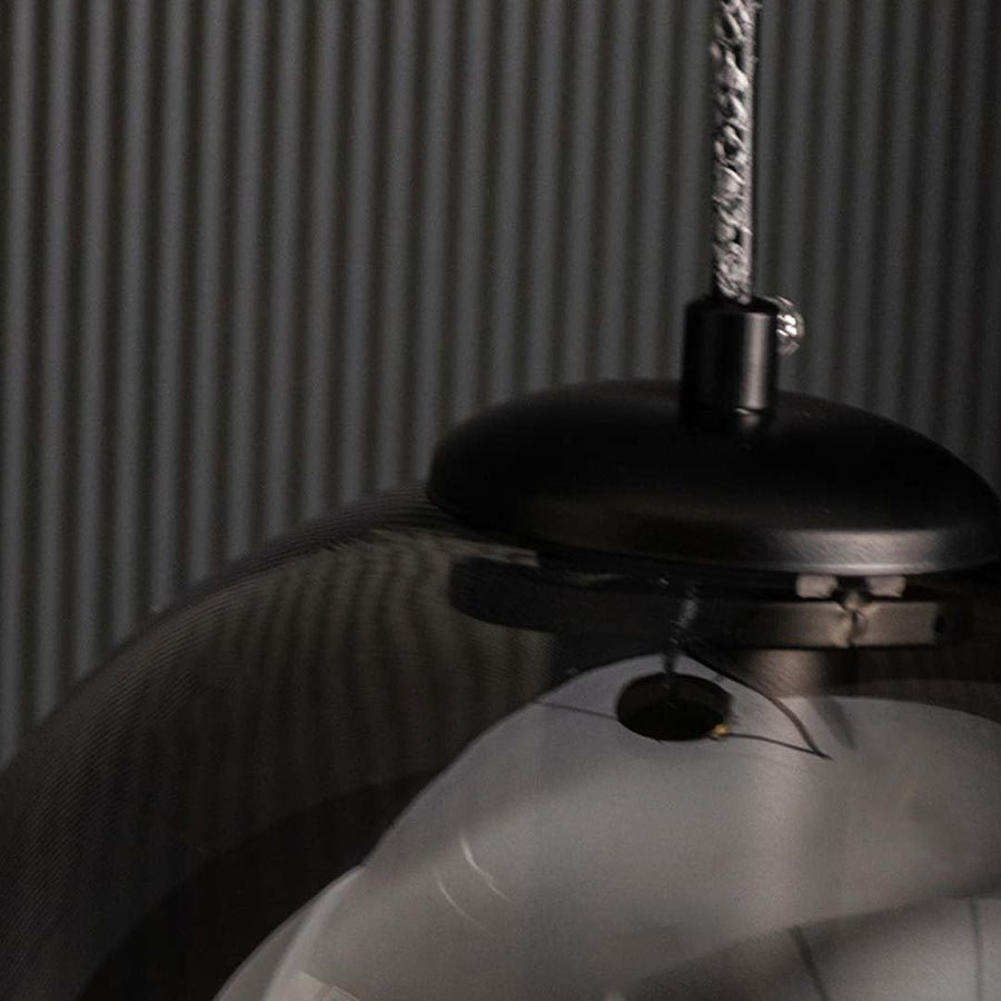 Closeup off Smoked black glass pendant light displayed unlit on a black background showcasing its sleek round form and modern decorative style.
