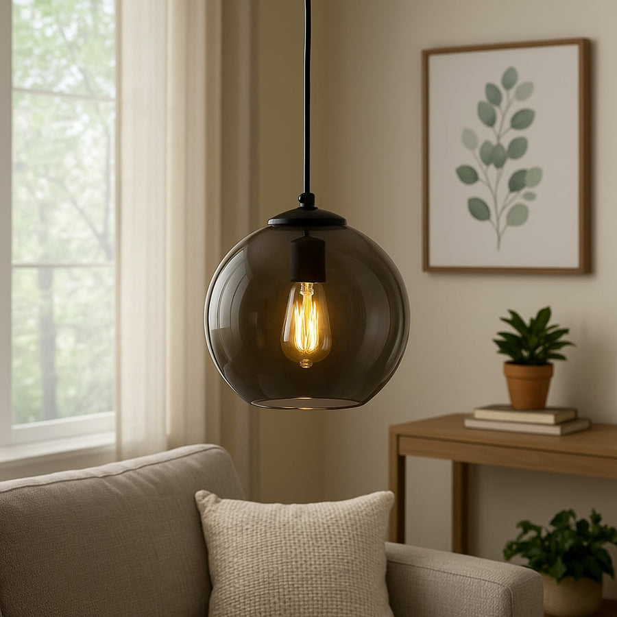 Smoked black glass globe pendant light with warm glowing filament bulb adding a modern elegant accent above a cozy sofa in a contemporary living room.