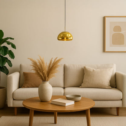 A gold metallic pendant light glowing warmly above a cozy neutral living room creating soft ambient lighting that enhances modern minimalist home decor.