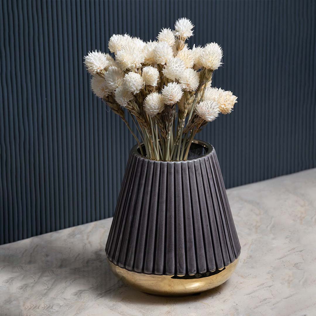 Elegant ribbed purple ceramic vase with golden base set against a dark background highlighting its smooth matte texture and metallic contrast.