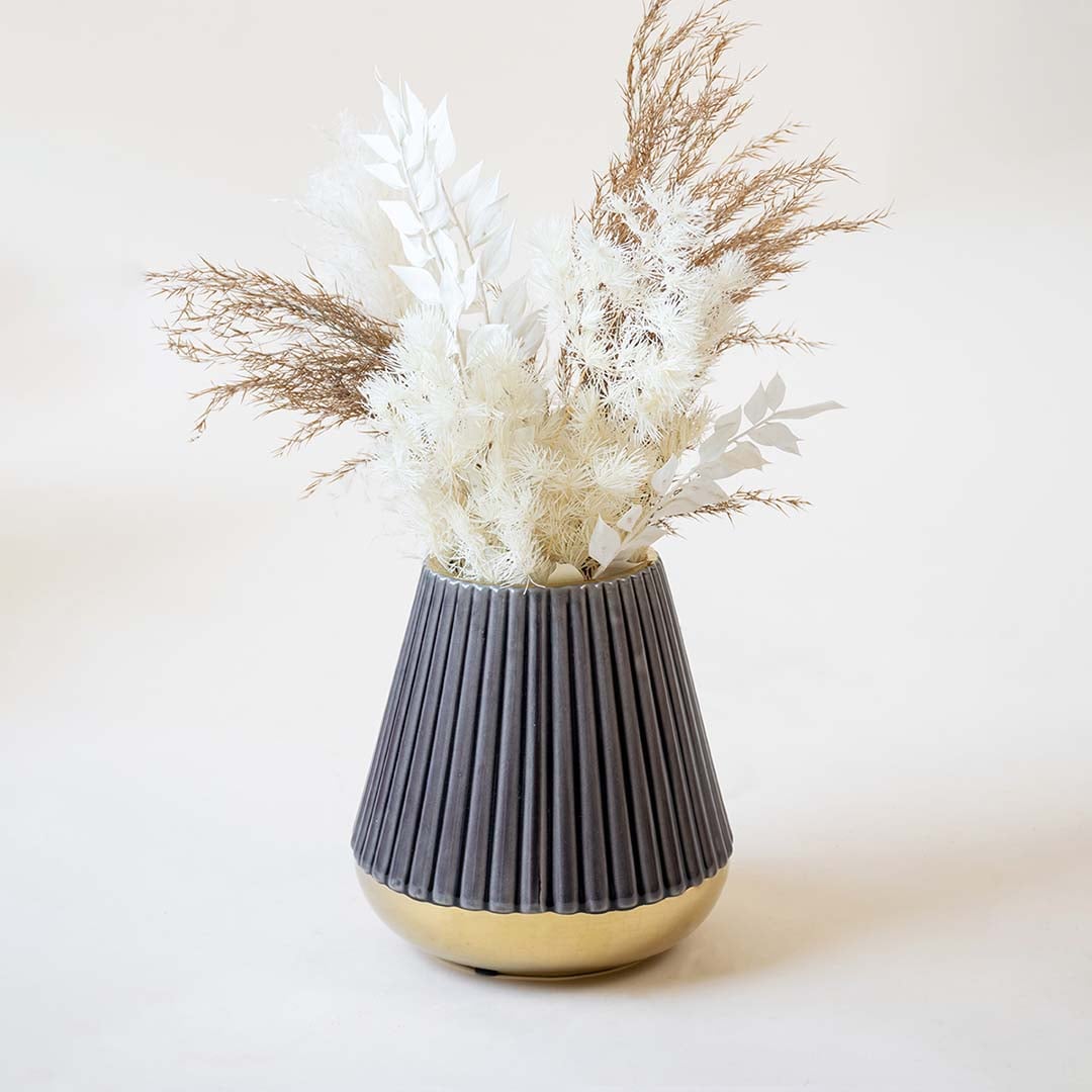 Stylish ribbed purple vase with glossy golden bottom captured on a white backdrop emphasizing its conical shape and refined detailing.