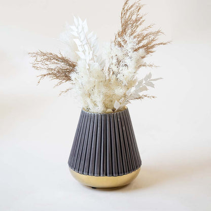 Stylish ribbed purple vase with glossy golden bottom captured on a white backdrop emphasizing its conical shape and refined detailing.