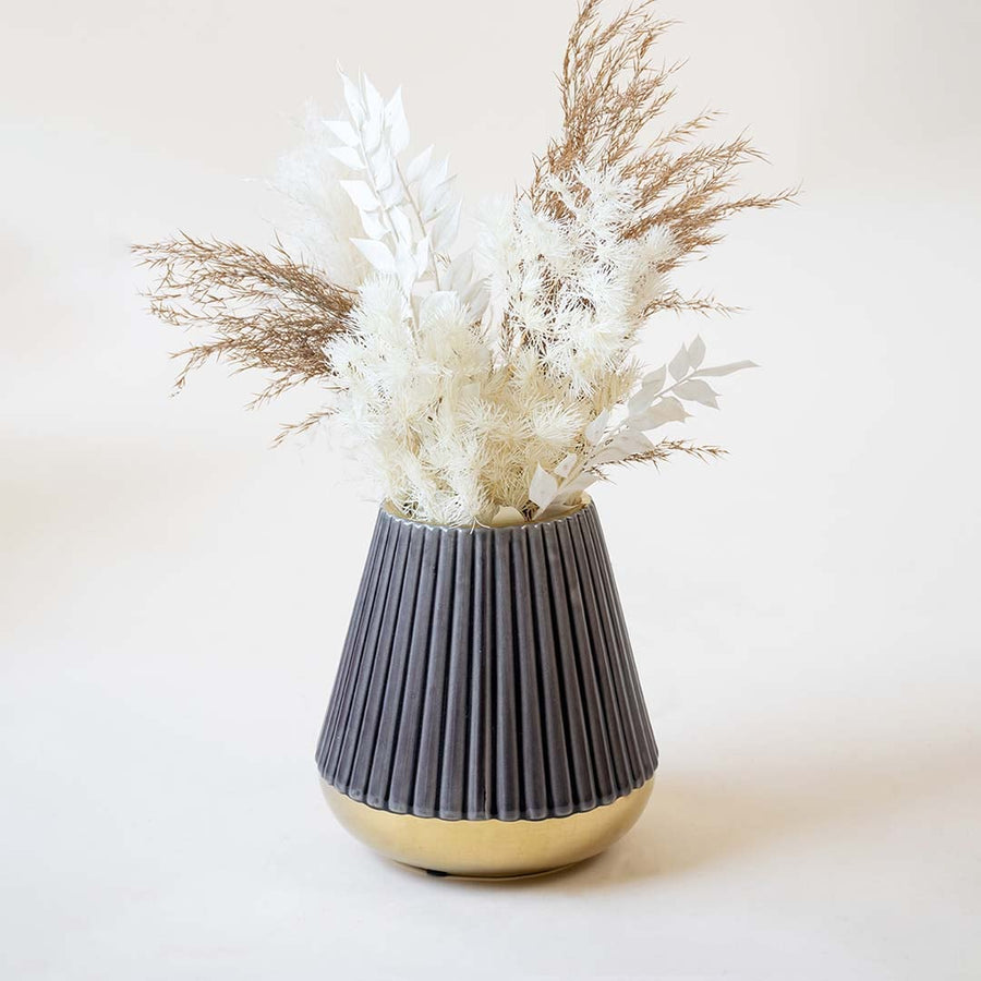 Stylish ribbed purple vase with glossy golden bottom captured on a white backdrop emphasizing its conical shape and refined detailing.