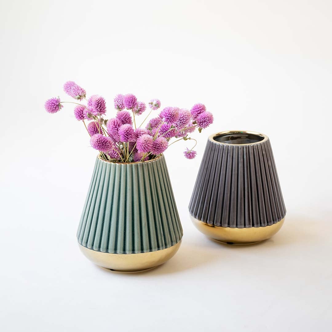 Set of modern matte green vase with vertical grooves and a glossy gold finish at the bottom presented against a white backdrop highlighting its texture and minimal design.