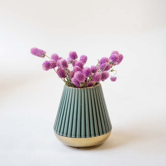 Decorative ceramic vase with ribbed green finish holding pink floral stems styled on table for modern home interior decor.