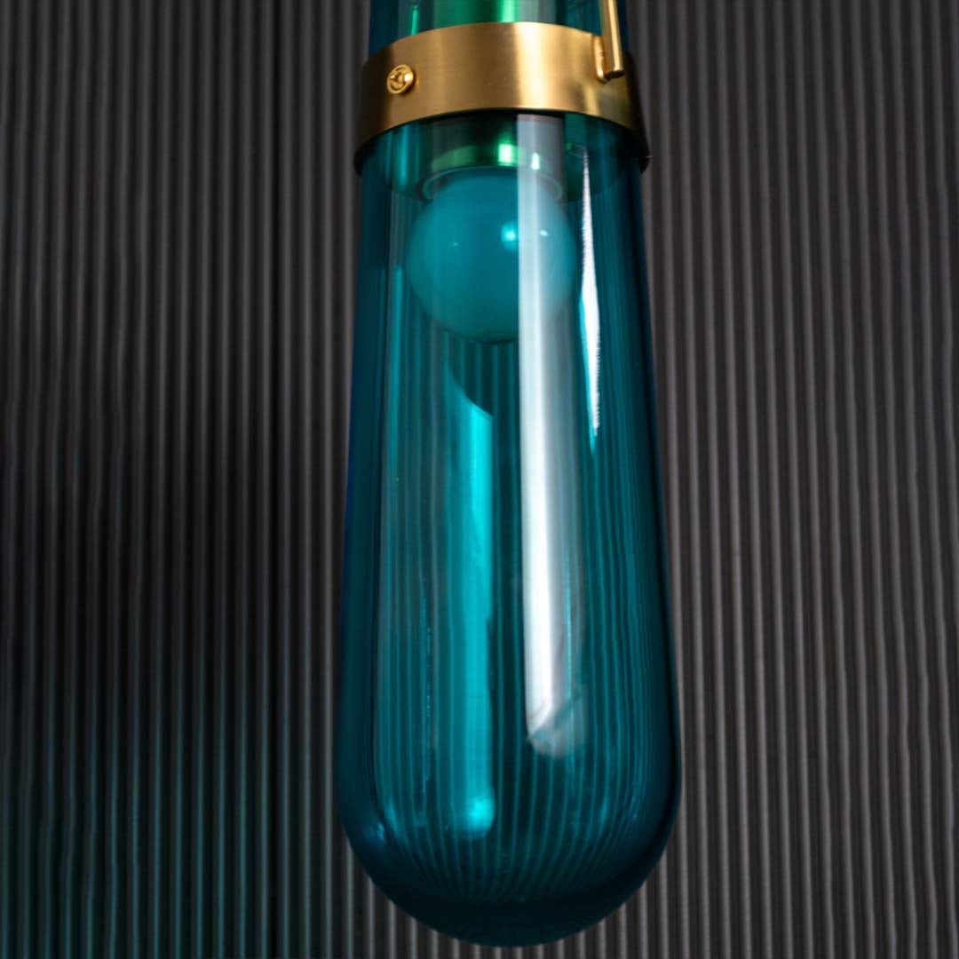 Detailed closeup of the pendant light showing the inner bulb structure and the blue glass enclosure with gold accents creating an elegant look.