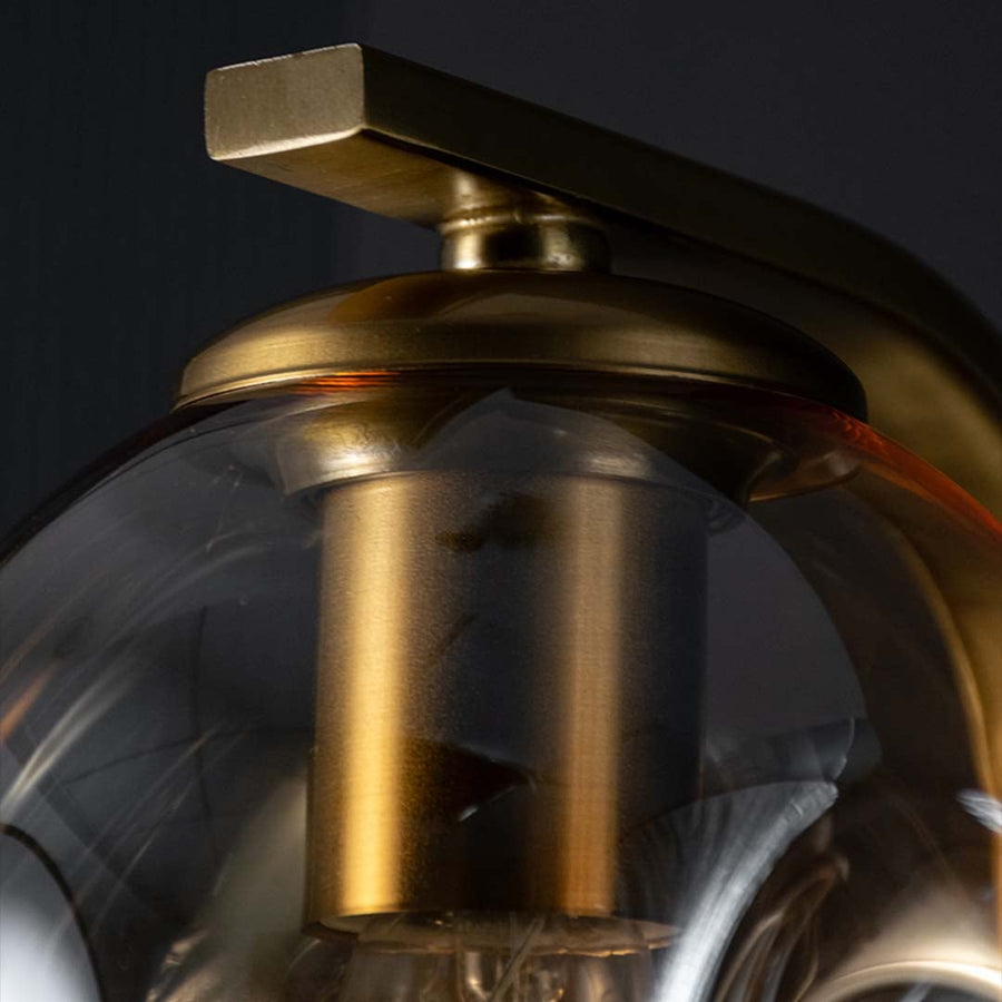 Detailed closeup of the sculpted glass shade showing smooth curves and golden fittings with the bulb glowing softly inside for a warm effect.