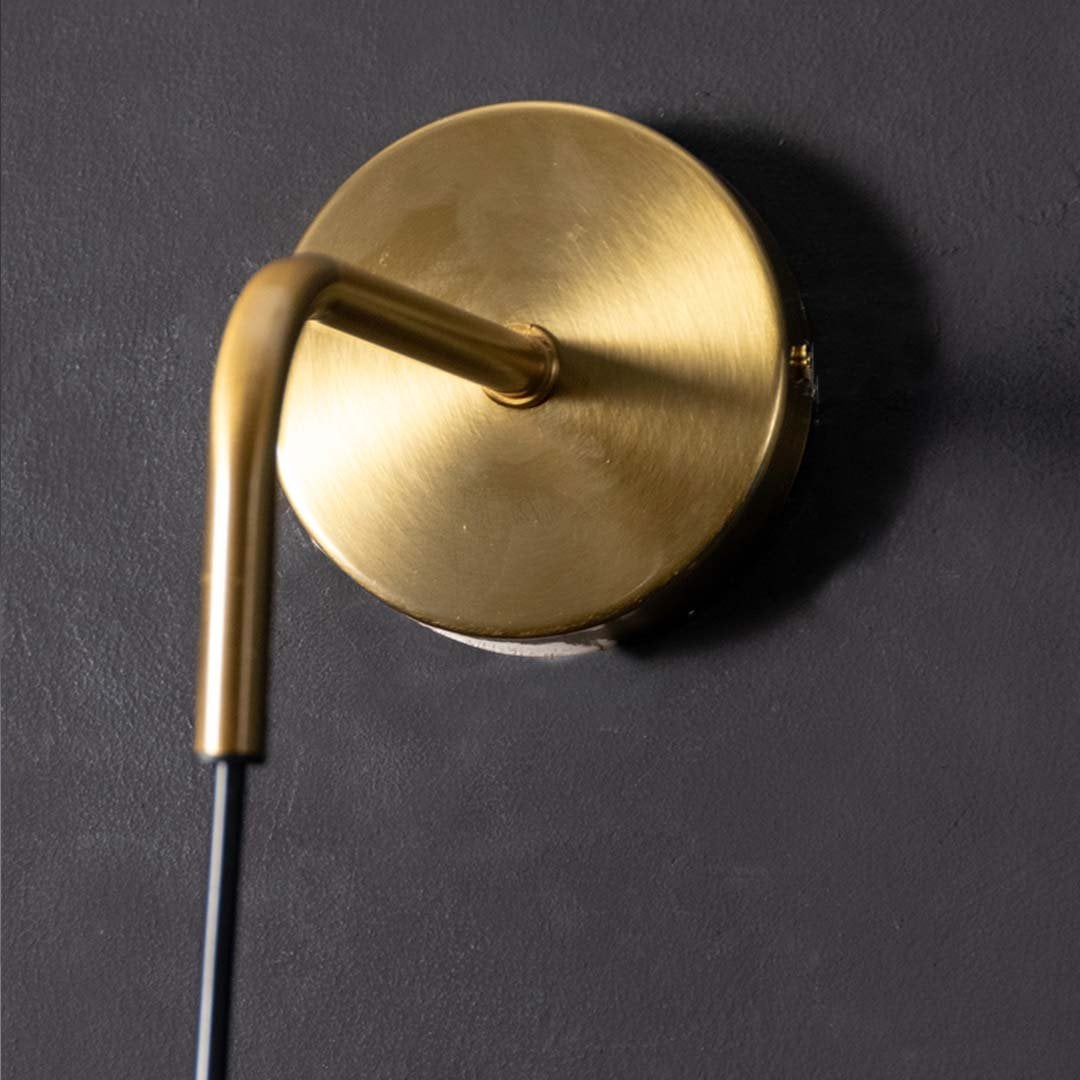 Macro shot of brushed gold wall mount and adjustable black cord of hanging sconce highlighting durable construction and sleek design.