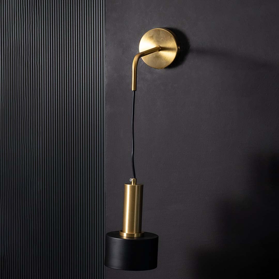 Sleek unlit wall lamp with brass mount and black cylinder spotlight shown on black background showcasing premium metal finish quality.