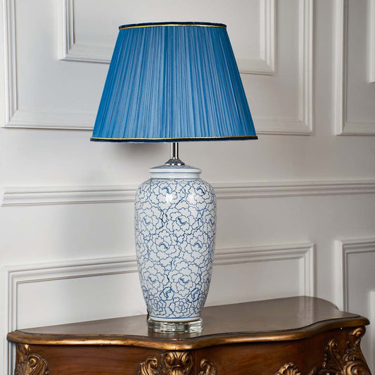 Blue floral ceramic table lamp with blue pleated shade displayed on a white background showcasing the floral pattern and smooth ceramic finish.