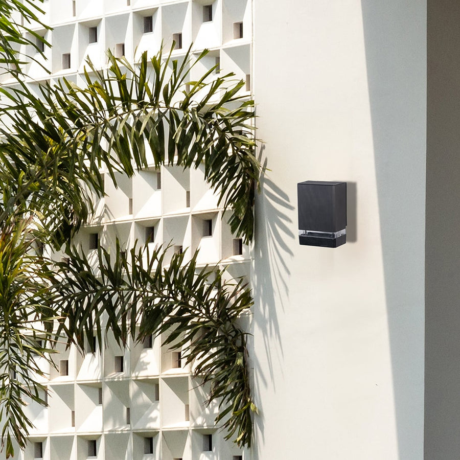 Black metal outdoor wall light lifestyle image on modern exterior wall for stylish entryway lighting decor.