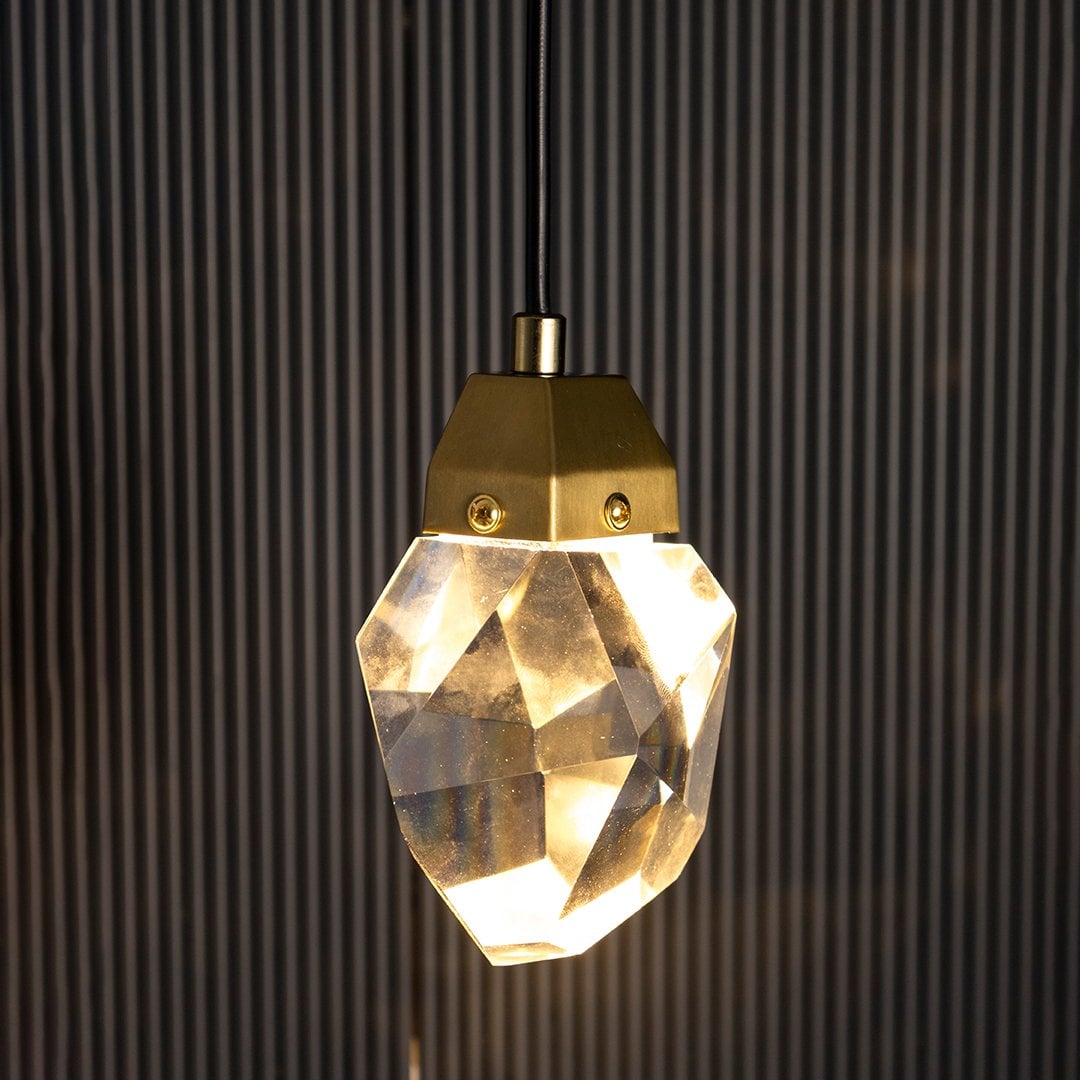 Crystal pendant light glowing warmly on black background creating a sophisticated and modern lighting aesthetic.