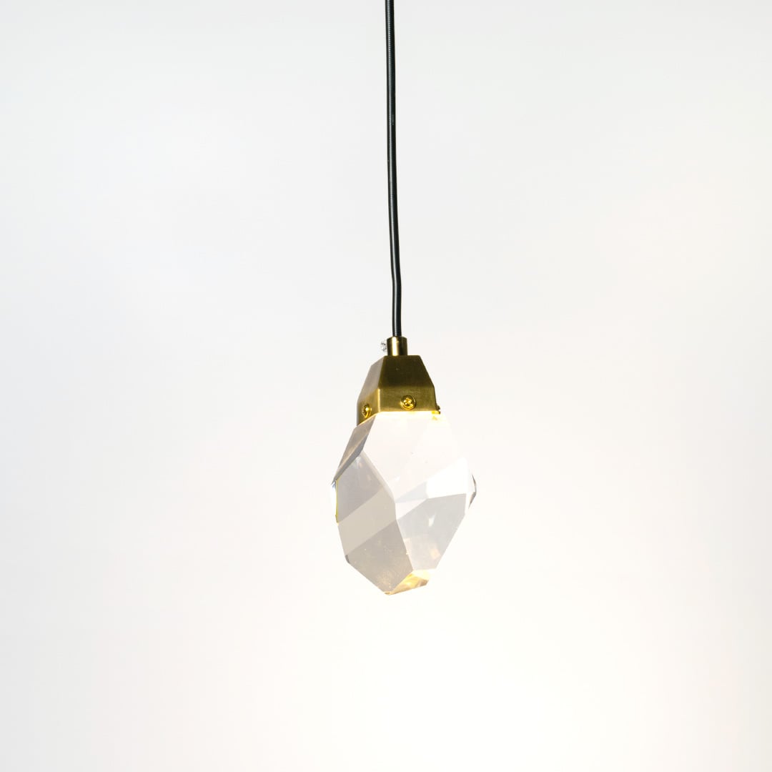 Crystal pendant lamp glowing softly with golden holder against white wall adding elegance to modern interiors.