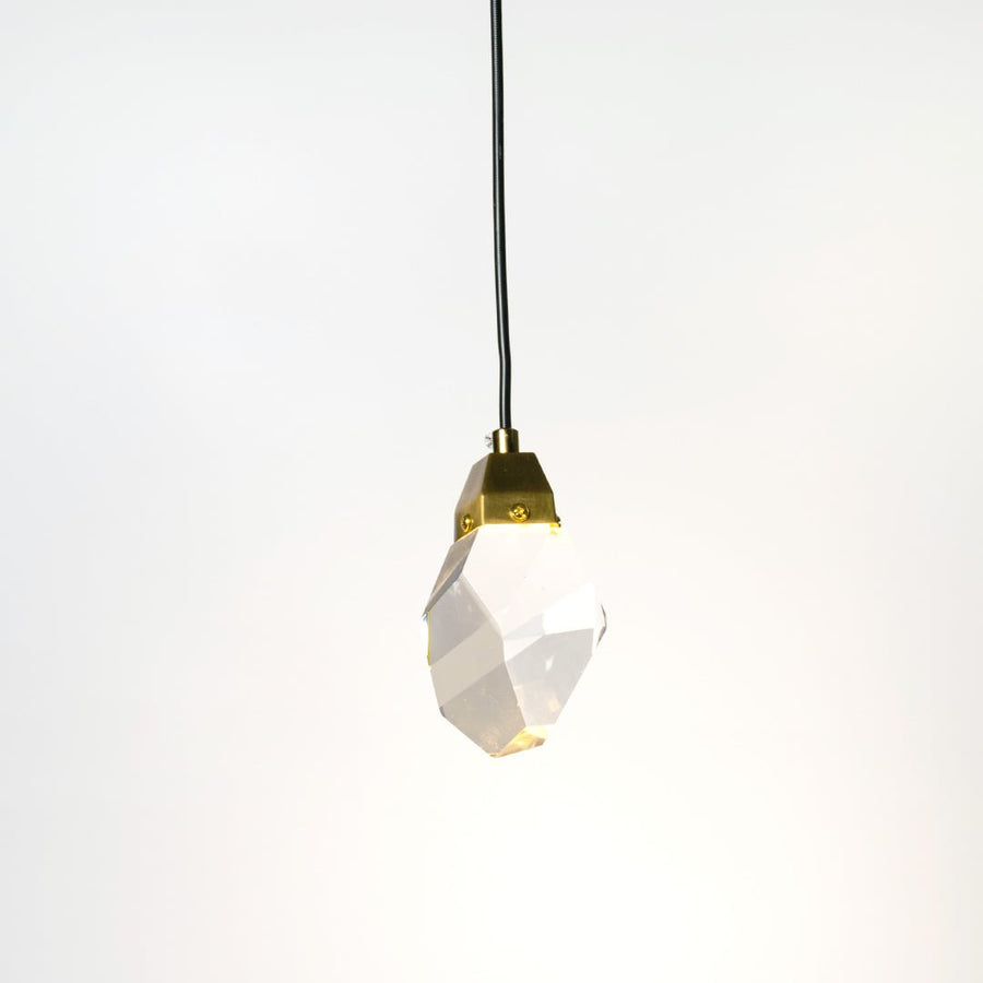 Crystal pendant lamp glowing softly with golden holder against white wall adding elegance to modern interiors.