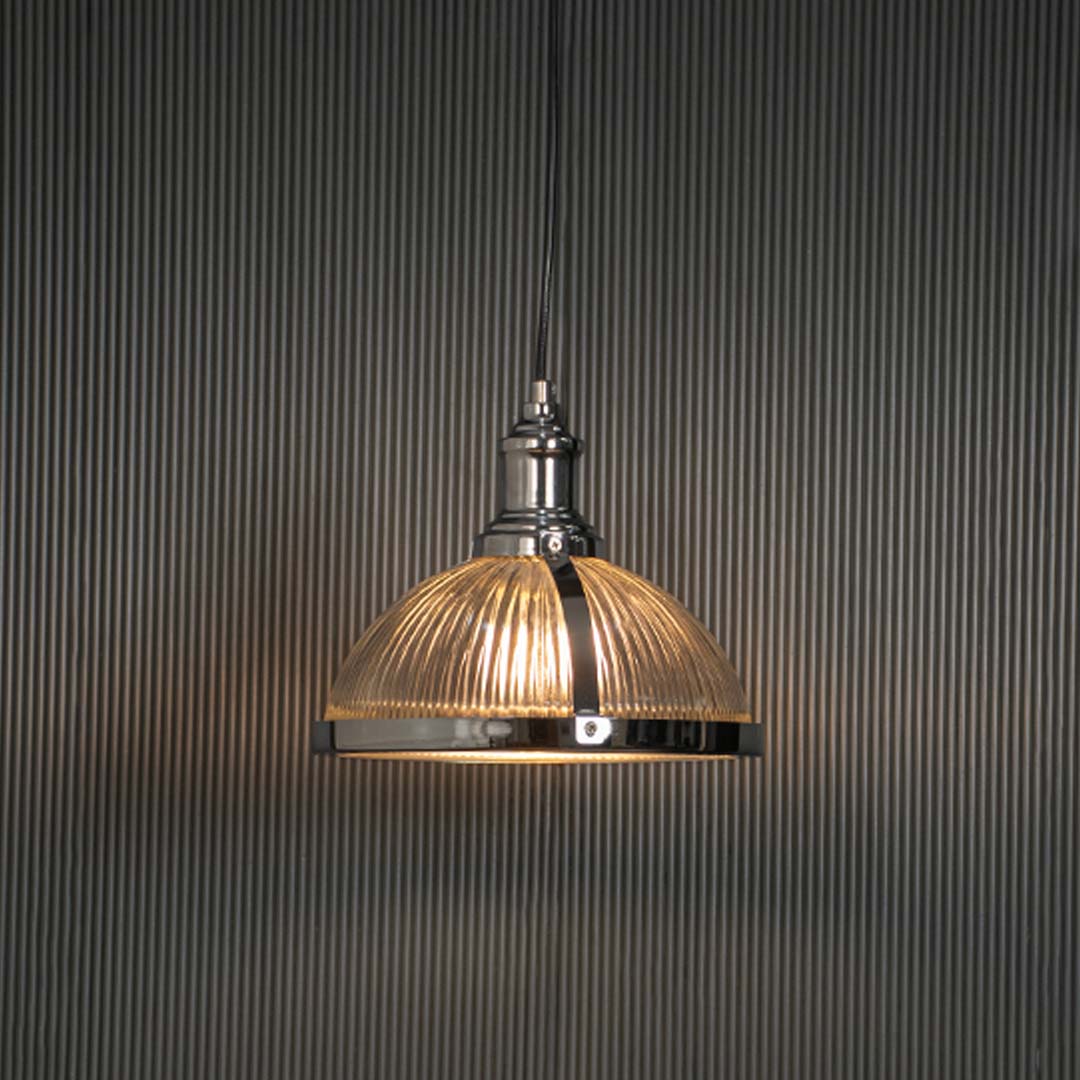 Clear ribbed glass pendant light with brushed brass finish glowing for modern interiors.