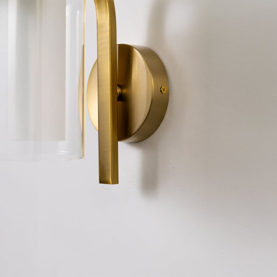 Elegant brass metal wall light with frosted glass shade and polished finish for luxury interiors.