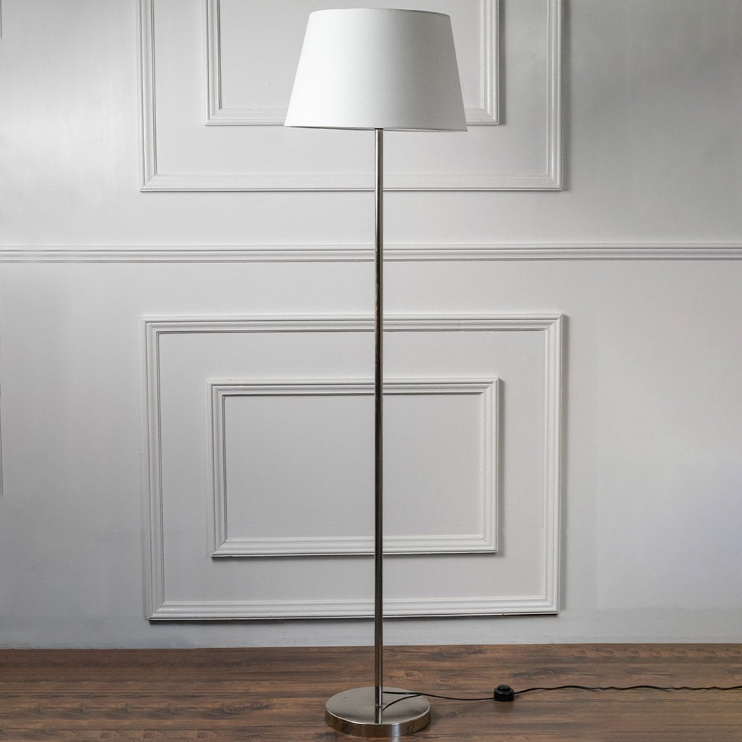 Modern floor lamp with slim chrome stand and white fabric shade on a plain background – minimalist home lighting.