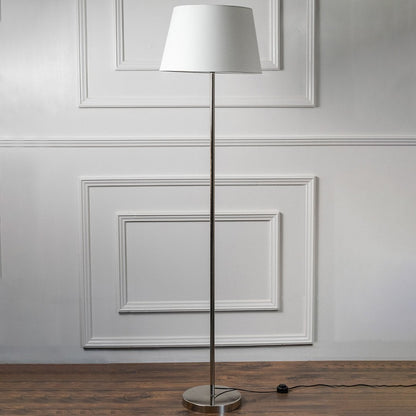 Modern floor lamp with slim chrome stand and white fabric shade on a plain background – minimalist home lighting.