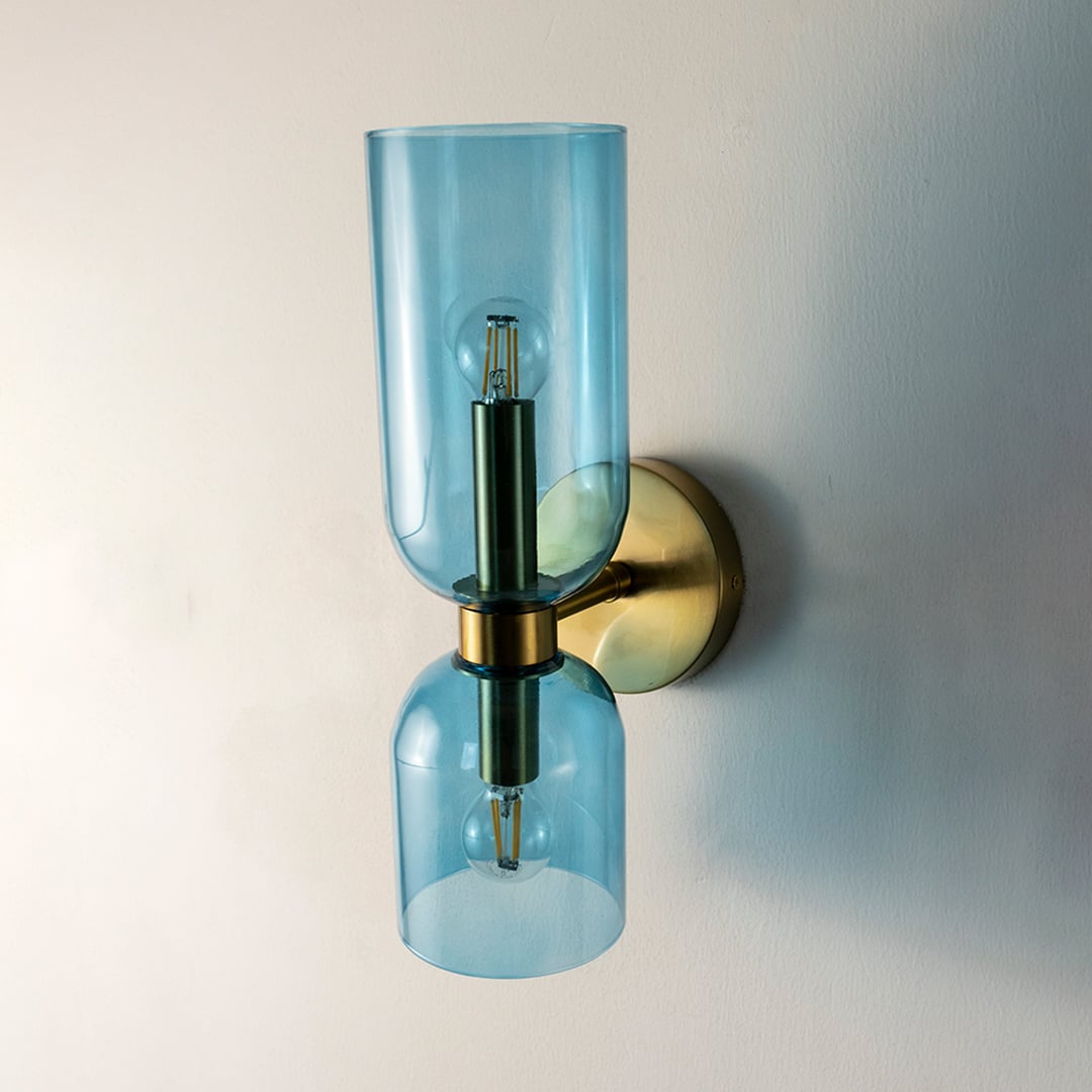 Stylish wall light with twin blue glass shades and gold base turned off on white background for decor display.