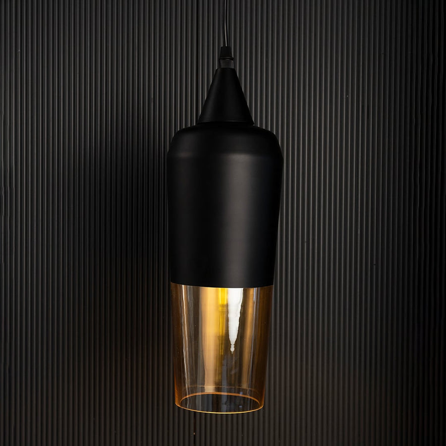 Amber glass and black metal pendant lamp turned off suspended against a dark black background highlighting the warm light.