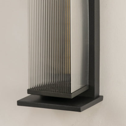 Closeup view of matte black metal frame and vertical ribbed glass texture of the modern outdoor wall lighting fixture detail.