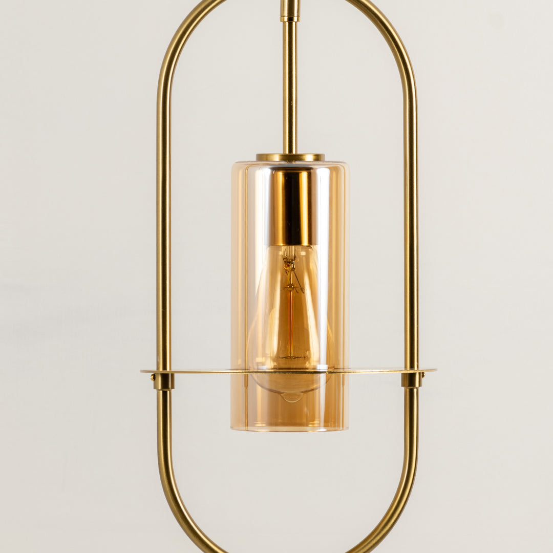 Closeup of gold metal pendant light with exposed bulb for elegant kitchen and dining room decor styling.