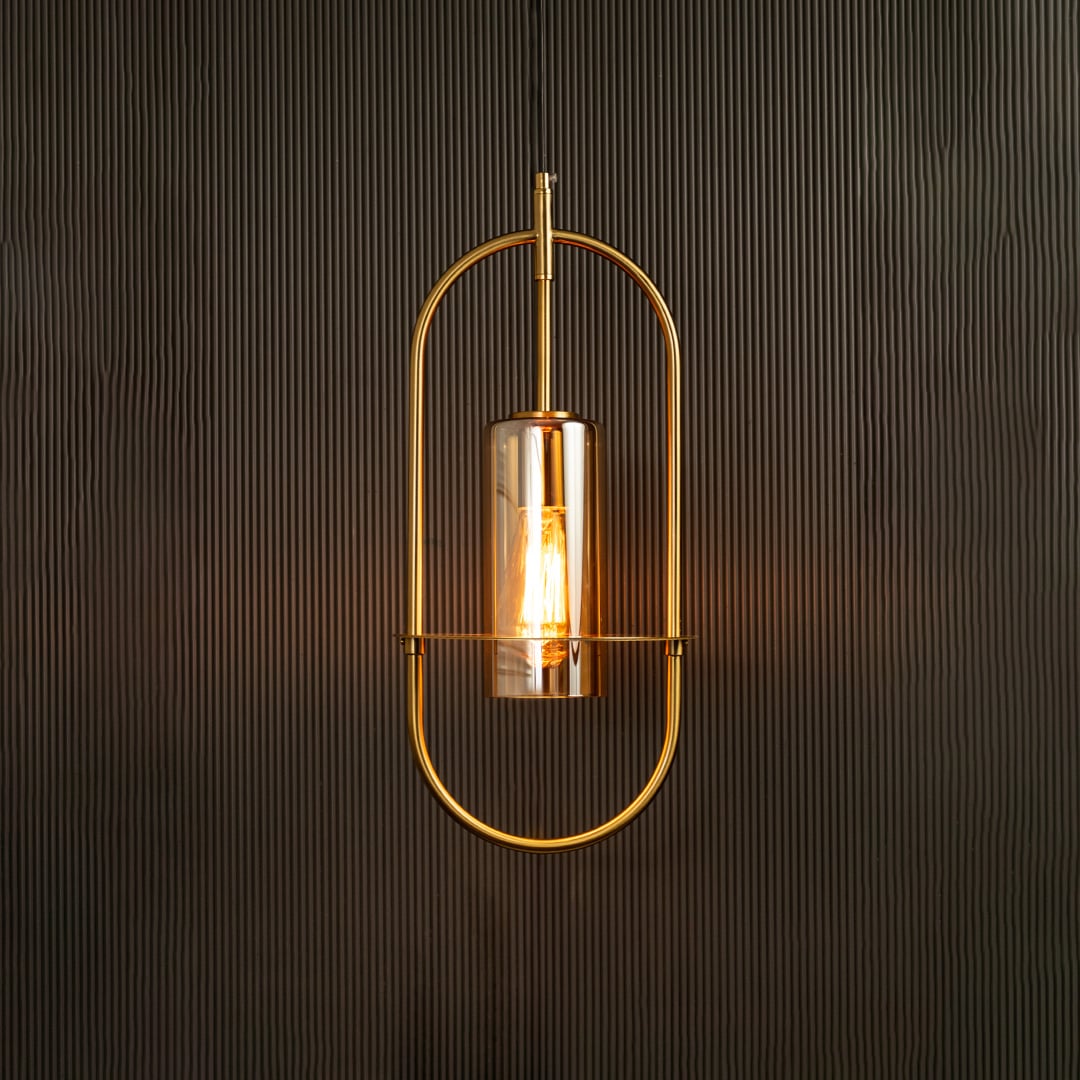 Hanging pendant light illuminated against a dark background emphasizing its curved metal frame and warm amber-toned light.