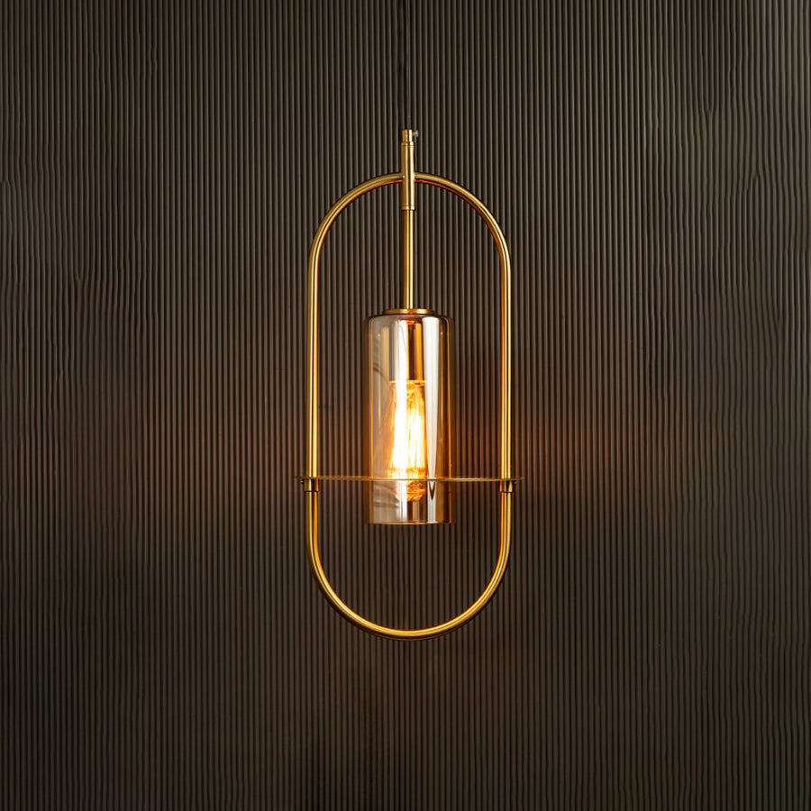 Hanging pendant light illuminated against a dark background emphasizing its curved metal frame and warm amber-toned light.