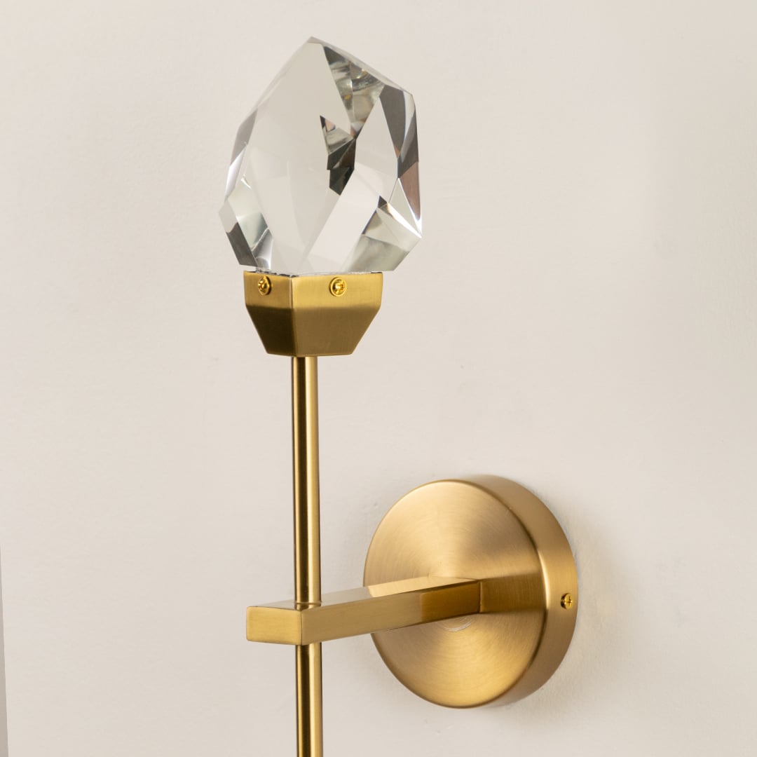 Closeup of crystal glass wall lamp with gold metal fixture showing luxury detail perfect for modern living room wall lighting.