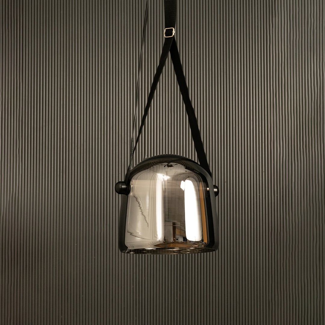 Modern chrome glass pendant lamp with black strap displayed on black background adding style to interior design.