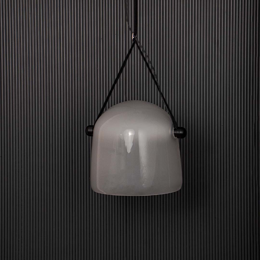 Frosted white glass pendant lamp with black strap displayed off on black background for premium interior look.