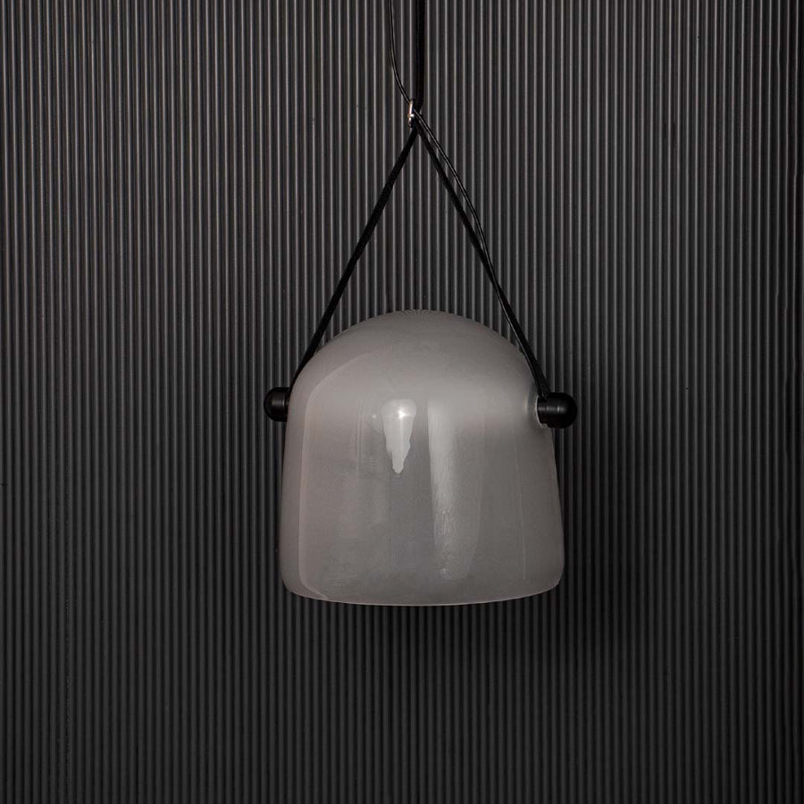 Frosted white glass pendant lamp with black strap displayed off on black background for premium interior look.