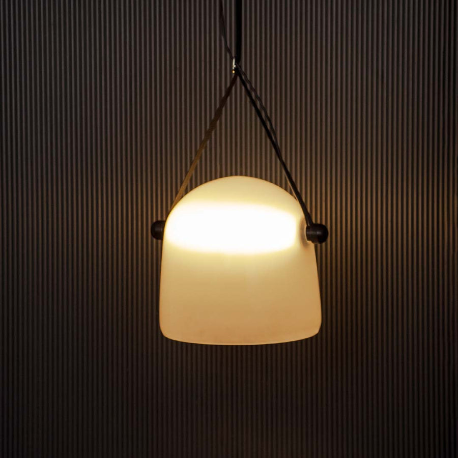 Frosted white glass pendant light glowing on black background perfect for stylish dining or living room lighting.
