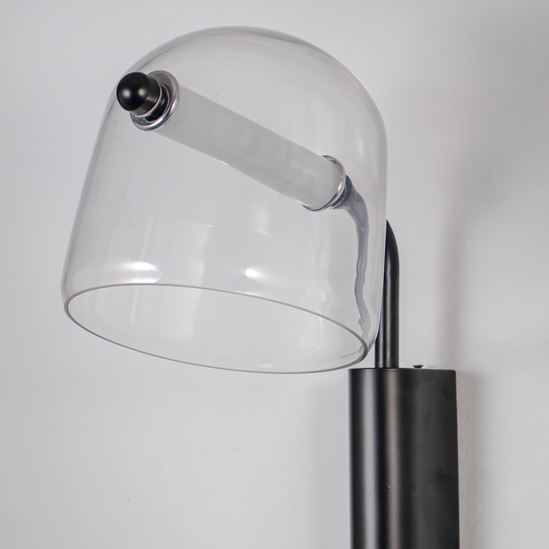 Closeup of clear glass wall lamp with black metal fixture showing minimalist design perfect for modern home wall lighting.